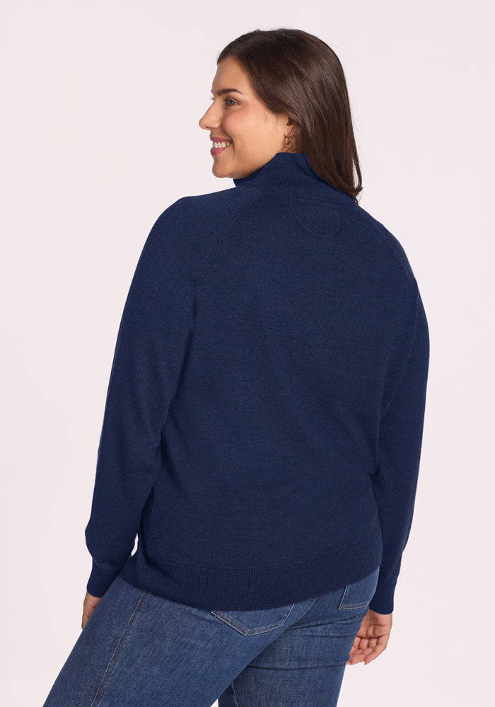 Woman smiling in Woolx Collins Half Zip Sweater - Ocean Cavern, shown from the back against a light background.