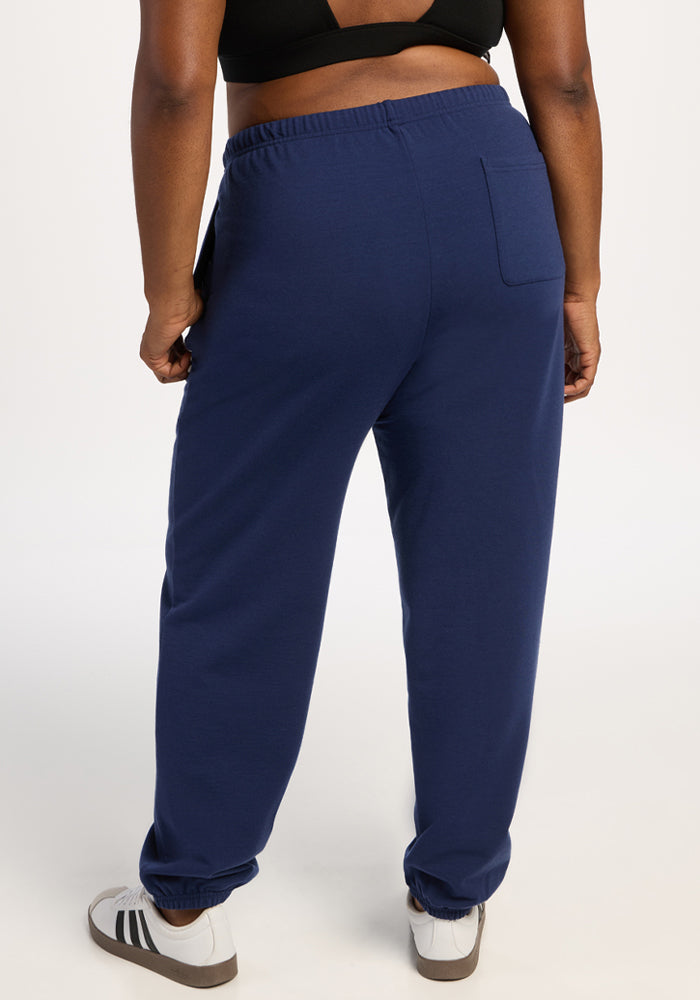 Model wears Woolx Juliette Joggers - Ocean Cavern, black top, white sneakers; shown from the back on white background.