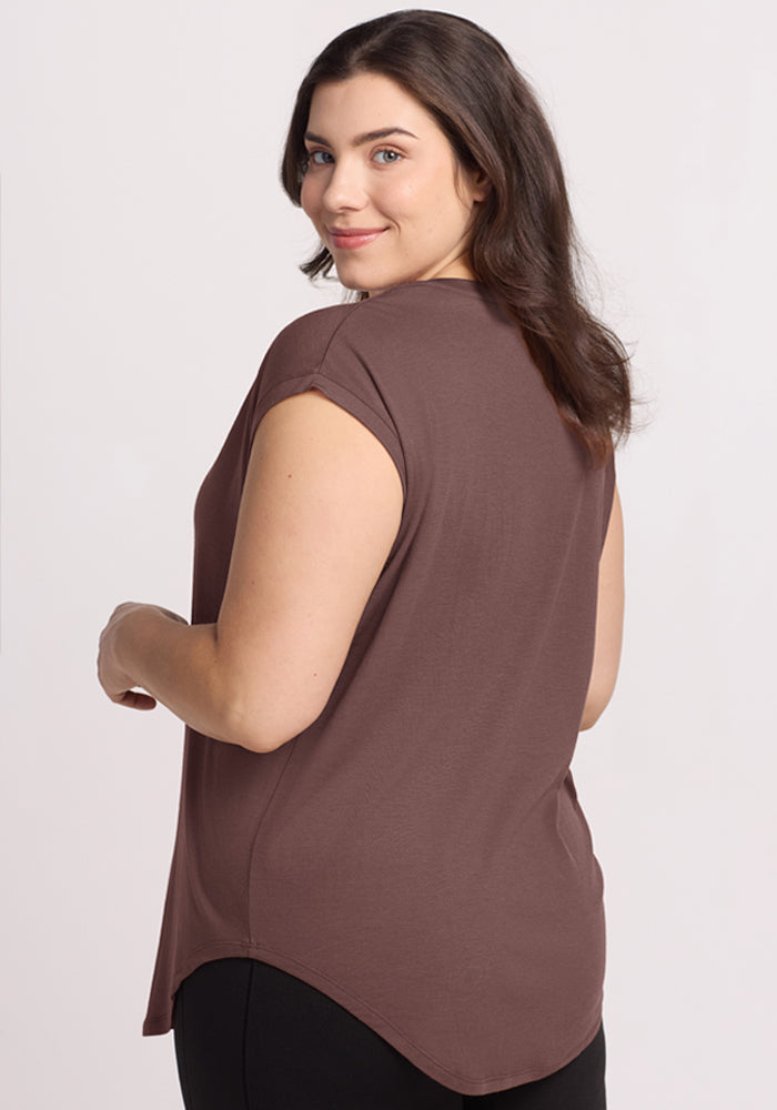 Woman with wavy dark hair in Woolx's Gabi Tunic Top in Peppercorn and black pants, smiling over her shoulder.