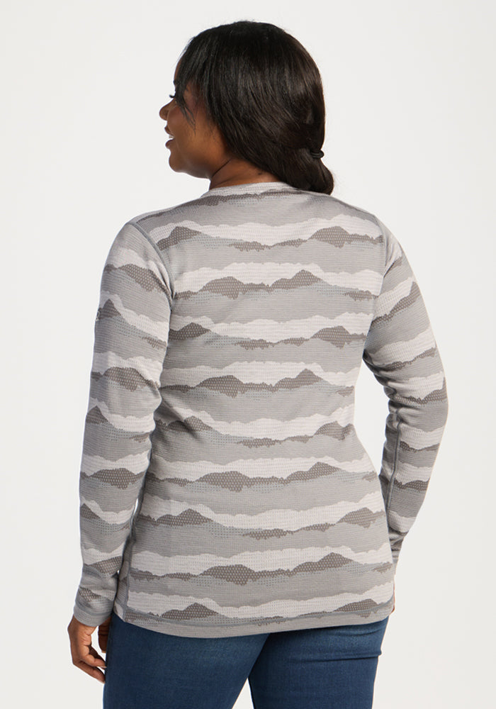 A woman in jeans and a Woolx Maddie Baselayer Top - High Peaks stands with her back to the camera.
