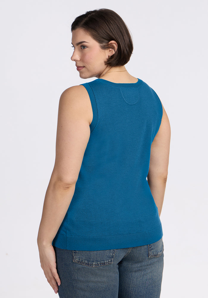 Woman in Woolx Chessy Tank Top - Blue Pine and jeans, seen from the back, looks over her shoulder.