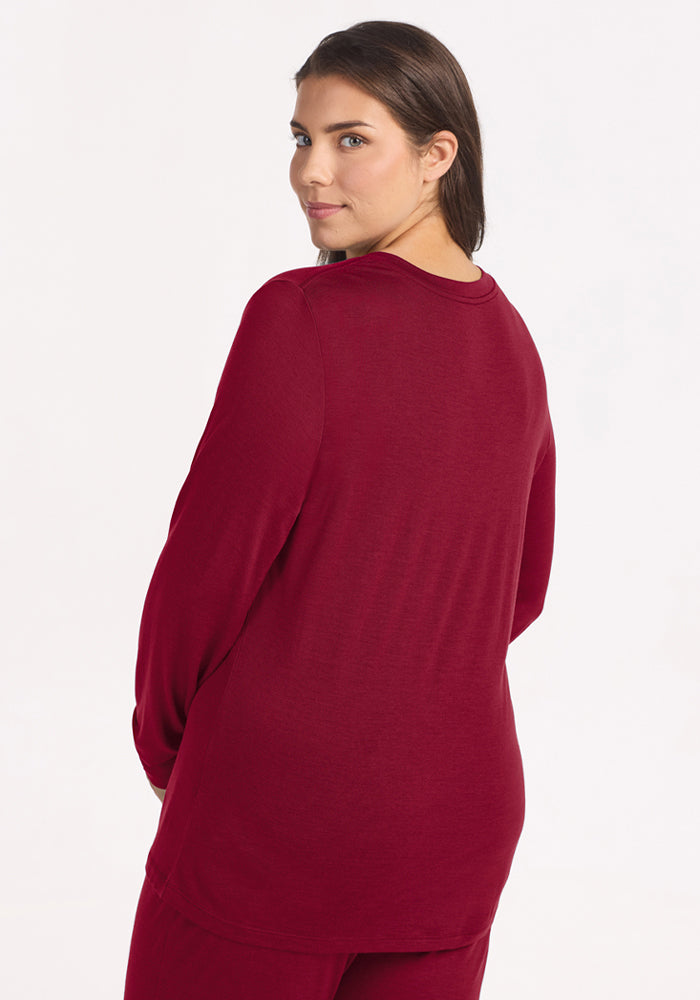 Back view of a person wearing a beet-red, long-sleeved Lily V Neck Lounge Top in Merino wool.