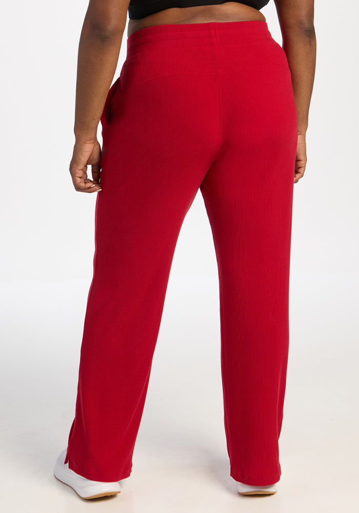 Model in Woolx Luca Ribbed Pants - Maraschino Cherry, white shoes, shown from the back on a white background.