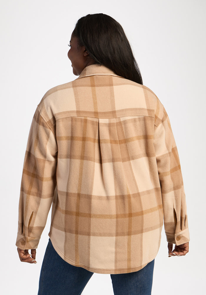 A woman wears the Woolx Sawyer Shacket in Saddleback Plaid with blue jeans, standing against a plain white background.