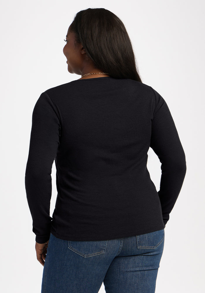 Woman with long dark hair wears Woolx Katie Ribbed Long Sleeve in black and blue jeans, shown from the back.