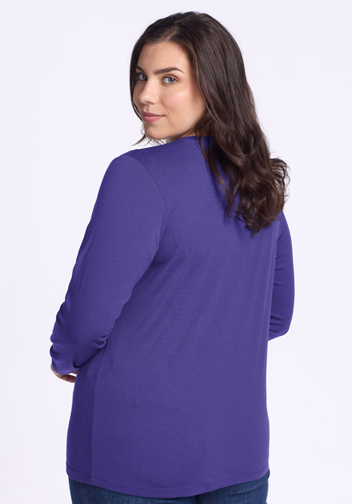 A woman in the Woolx Millie Long Sleeve - Berry Indigo looks over her shoulder, showcasing temperature-regulating style.
