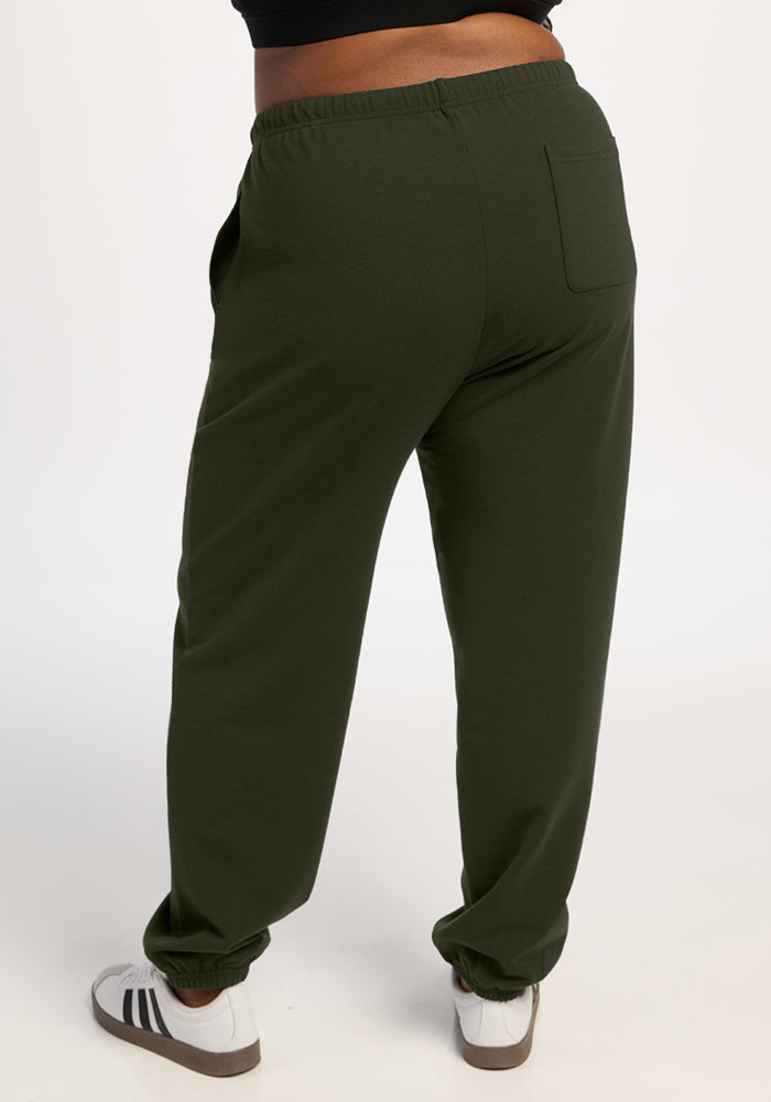 Model wears Woolx Juliette Joggers in Duffel Bag with white sneakers, shown from the back on plain background.