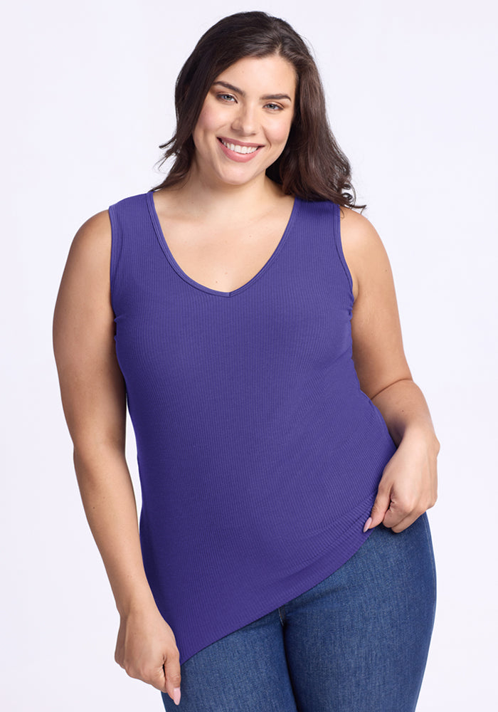 Smiling woman in a Woolx Vivi Ribbed Tank - Berry Indigo and blue jeans against a light background. 