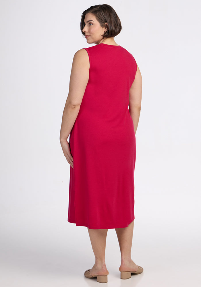 A woman with short brown hair, in the Woolx Cassie Dress - Poppy Spark and beige sandals, stands facing away with her head turned slightly to the side against a plain white background.