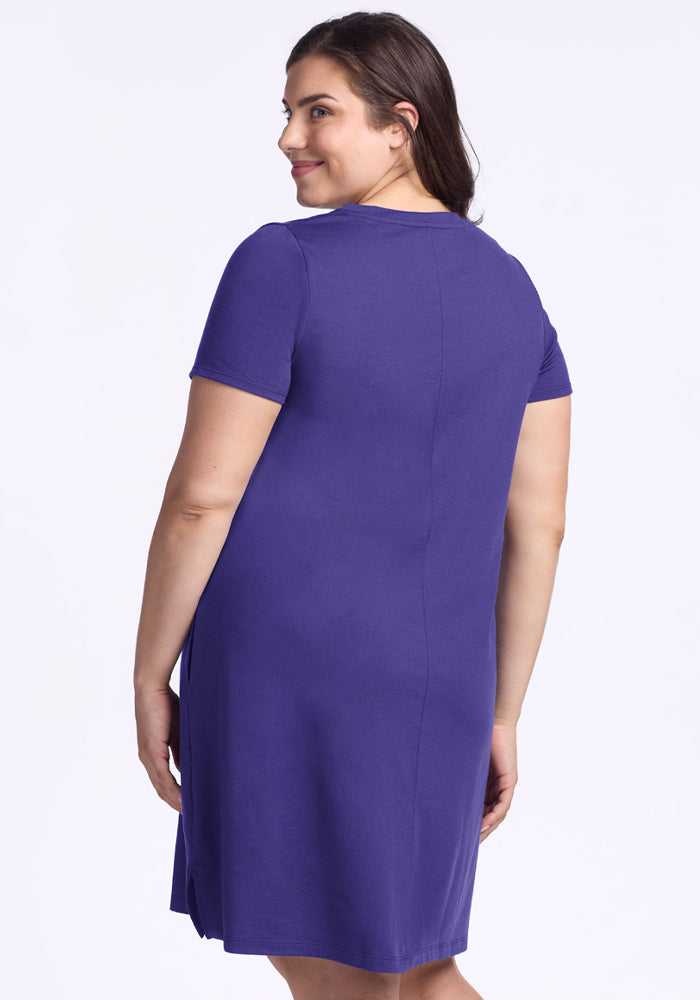 Smiling woman in a Woolx Georgie Dress - Berry Indigo, short-sleeve and knee-length, looks over her shoulder away from camera.