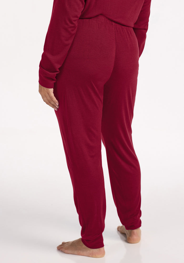 Back view of a person wearing deep red Woolx Mary Kate Lounge Pants with an elastic waistband and cuffed hems.