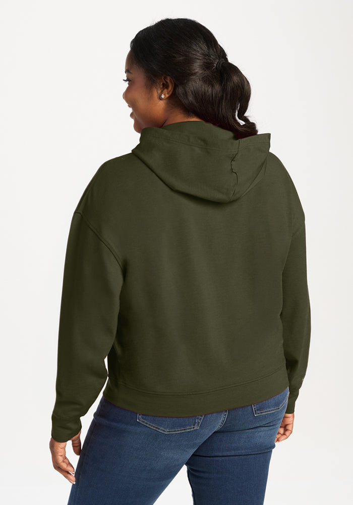 Woman in a Woolx Lizzy Hoodie - Everleaf and blue jeans, facing away from the camera against a plain background.