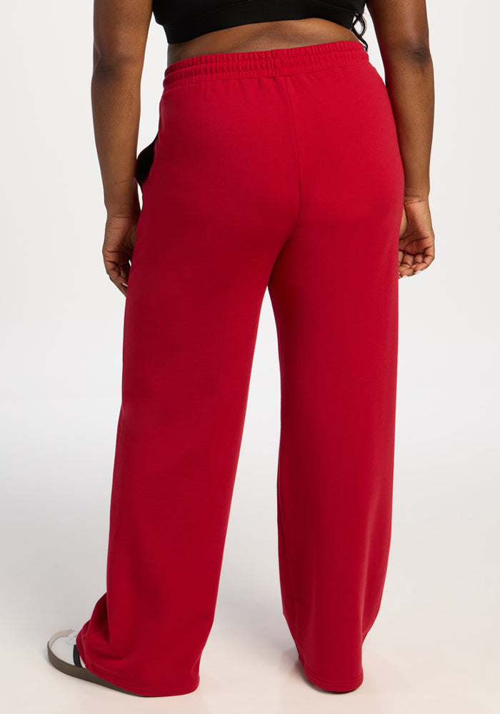Model in Woolx Eloise Wide Leg Pants - Maraschino Cherry and black top, shown from the back on white background.