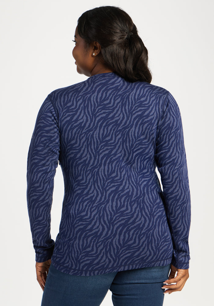 Woman facing away in Woolx Maddie Baselayer Top - Midnight Safari, a blue zebra print merino wool top, and blue jeans.