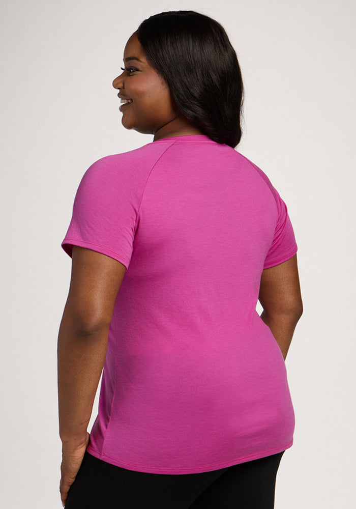 A woman in the Woolx Mia V Neck - Summer Sorbet stands turned to the side, smiling.