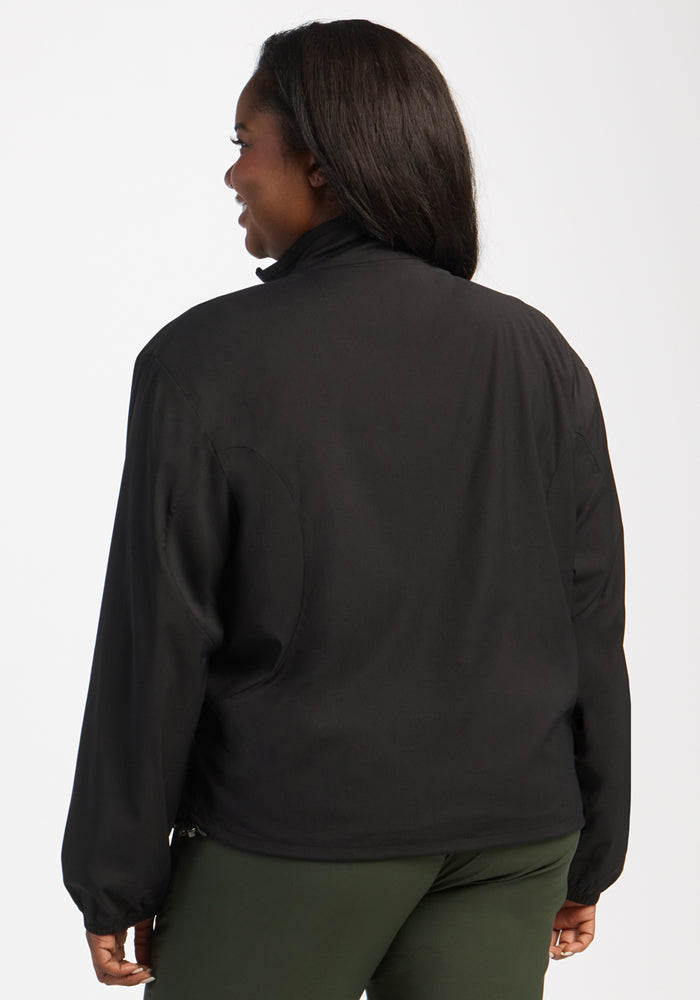 A woman models the Woolx Cooper Windbreaker - Black and green pants, seen from the back on a white background.