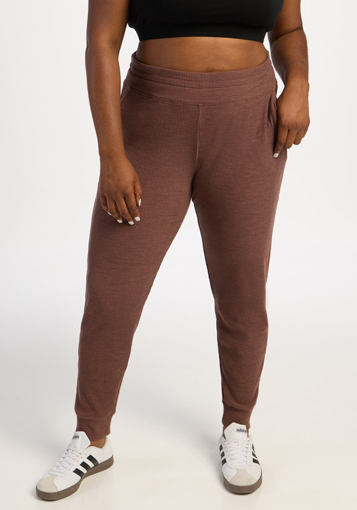 Model in Woolx Lennon Ribbed Joggers - Sable Heather, black crop top, and white sneakers against a white backdrop. 