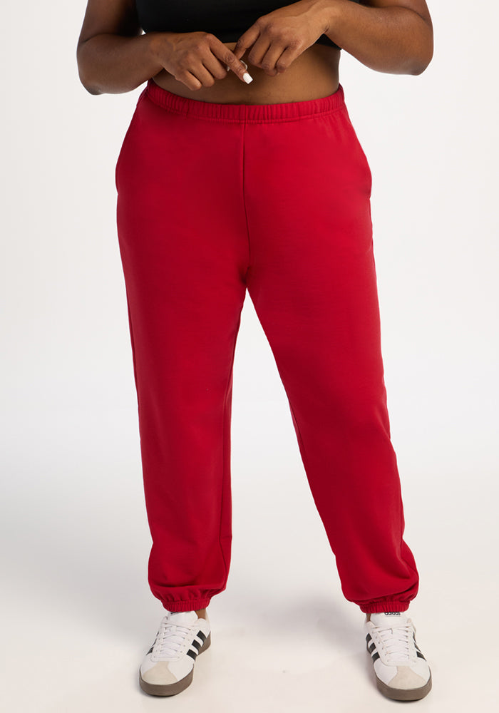 Model in Woolx Juliette Joggers - Maraschino Cherry, white sneakers, black top; plain white background. 