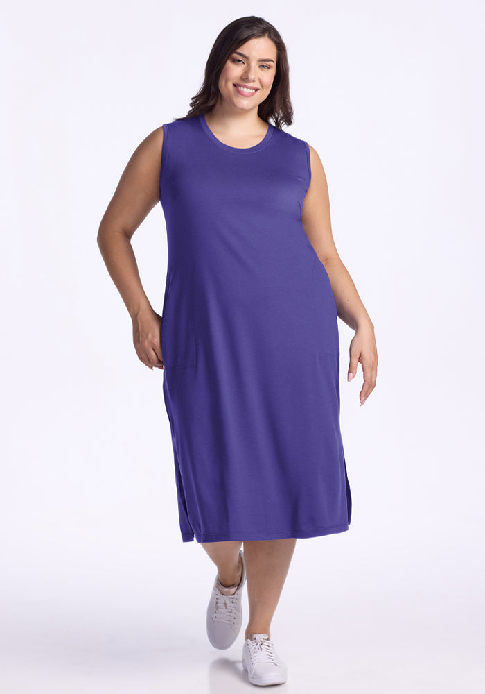 A woman in the Woolx Cassie Dress - Berry Indigo and white sneakers smiles against a plain white background. 