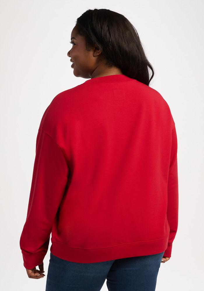 A woman seen from the back wearing a red Woolx Molly Crewneck - Maraschino Cherry and blue jeans.