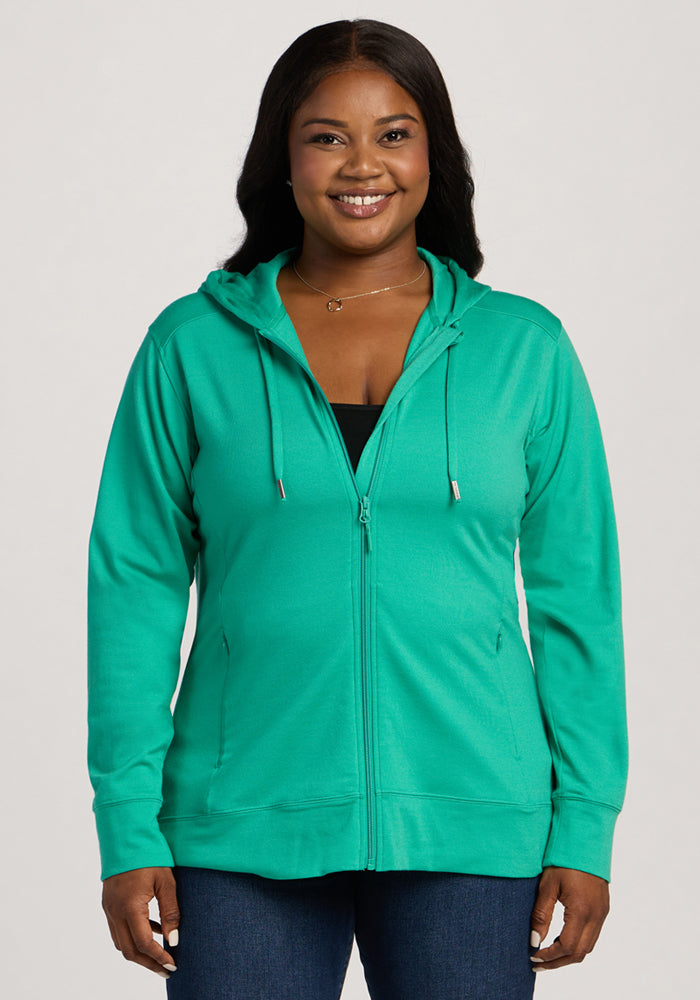 Woman smiling in the Woolx Ryann Hoodie - Jungle, a travel essential, layered over a black top. 