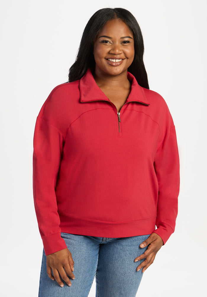 A woman wearing a red Tori 1/4 Zip - Maraschino Cherry merino wool long-sleeved quarter zip pullover. 