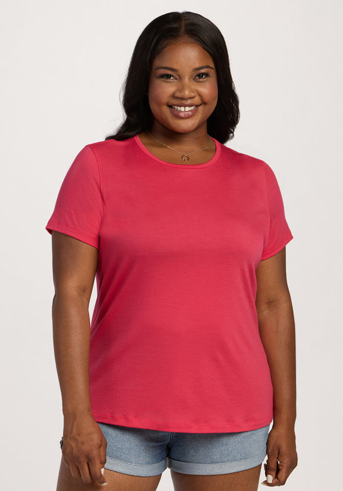 Woman smiling in the Woolx Liza Crew Neck Tee - Berry Ice Pop, paired with denim shorts against a light background. 