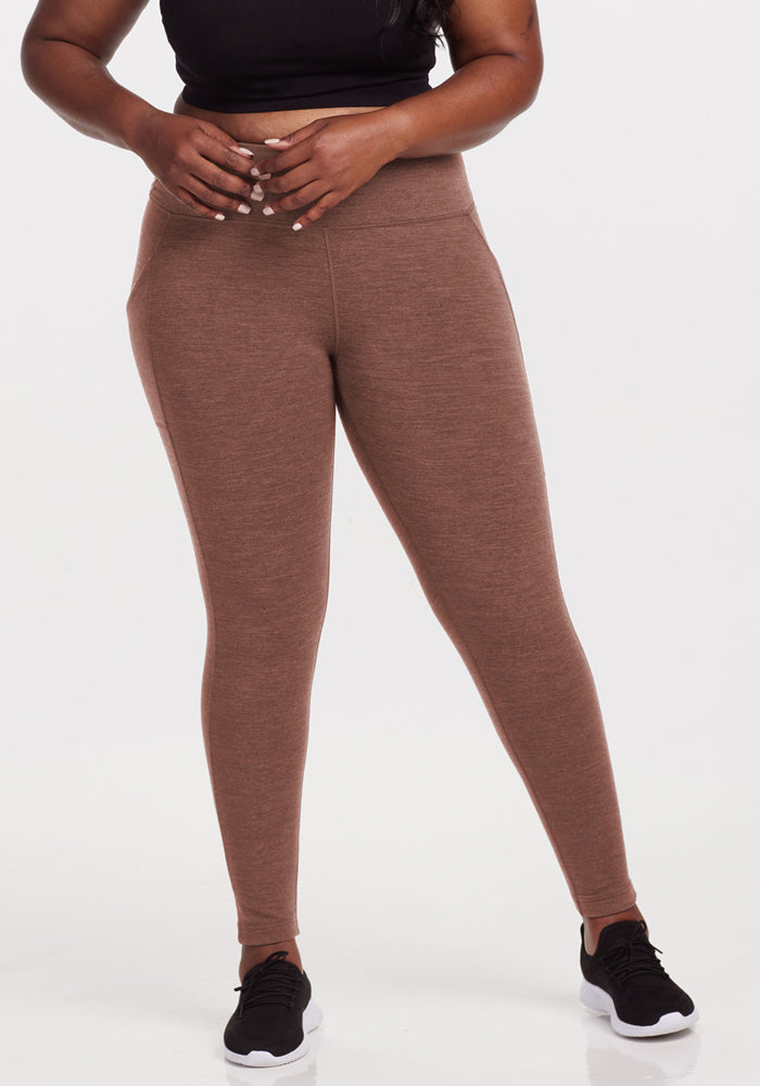 Woman in Woolx Piper Pocket Leggings - Sable Heather, black crop top, and sneakers stands against a white background. 