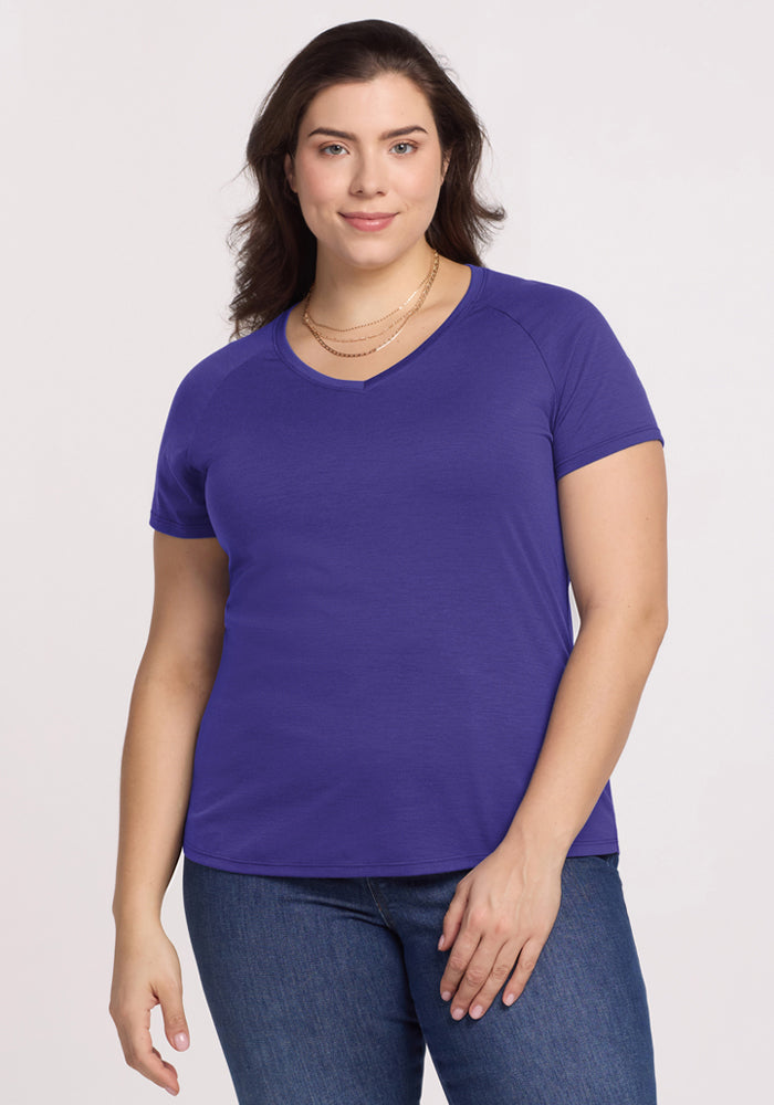 Smiling woman in Woolx Mia V Neck - Berry Indigo tee and jeans, facing the camera against a plain background. 