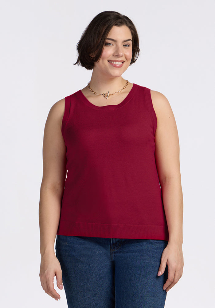 Woman with short brown hair wears a Woolx Chessy Tank Top in Beet Red, jeans, and a gold necklace, smiling at camera. 