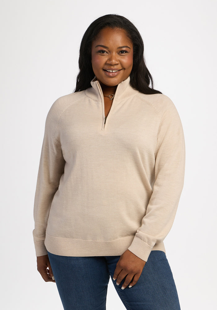 Woman in Woolx Collins Half Zip Sweater - French Oak and blue jeans smiles at camera against a white background. 