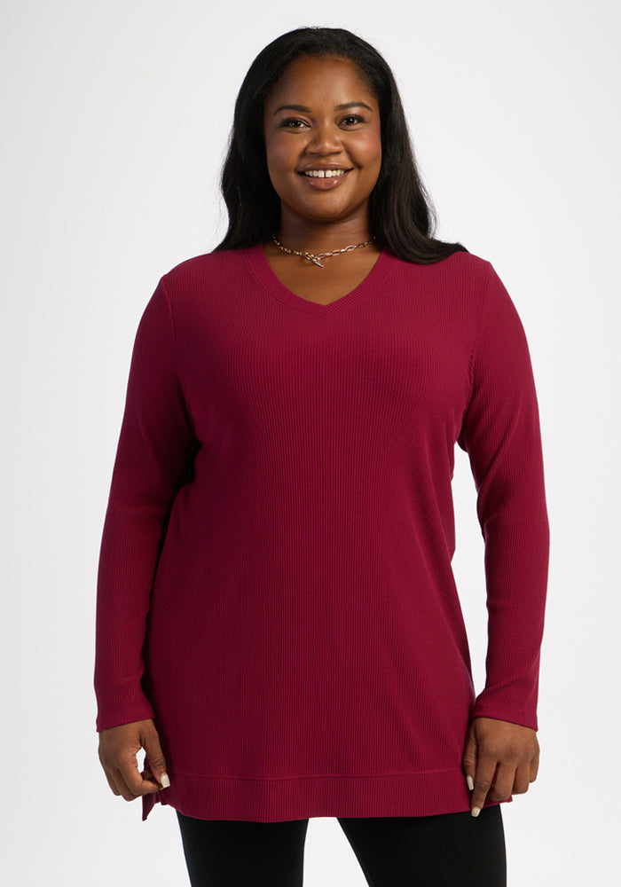 Smiling woman wears the Woolx Evie Ribbed Tunic in Beet Red with black pants, posed against a white background. 