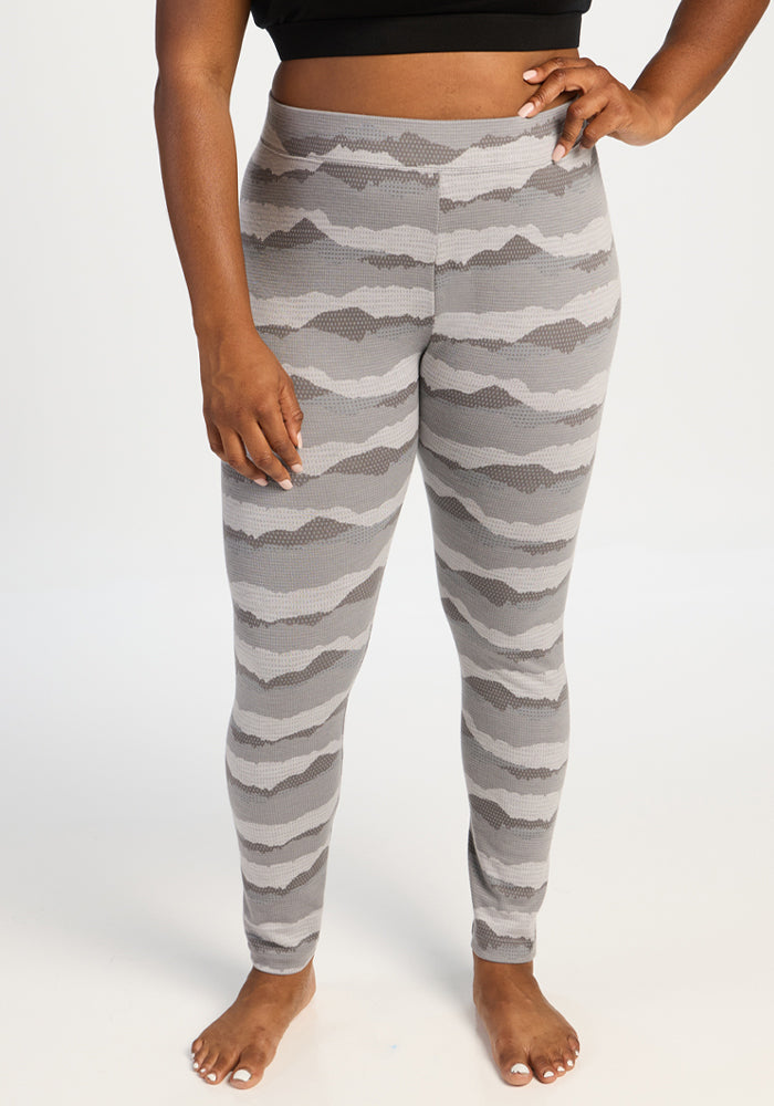 Person in Woolx Taylor Baselayer Leggings - High Peaks and a black crop top stands barefoot on a white background. 