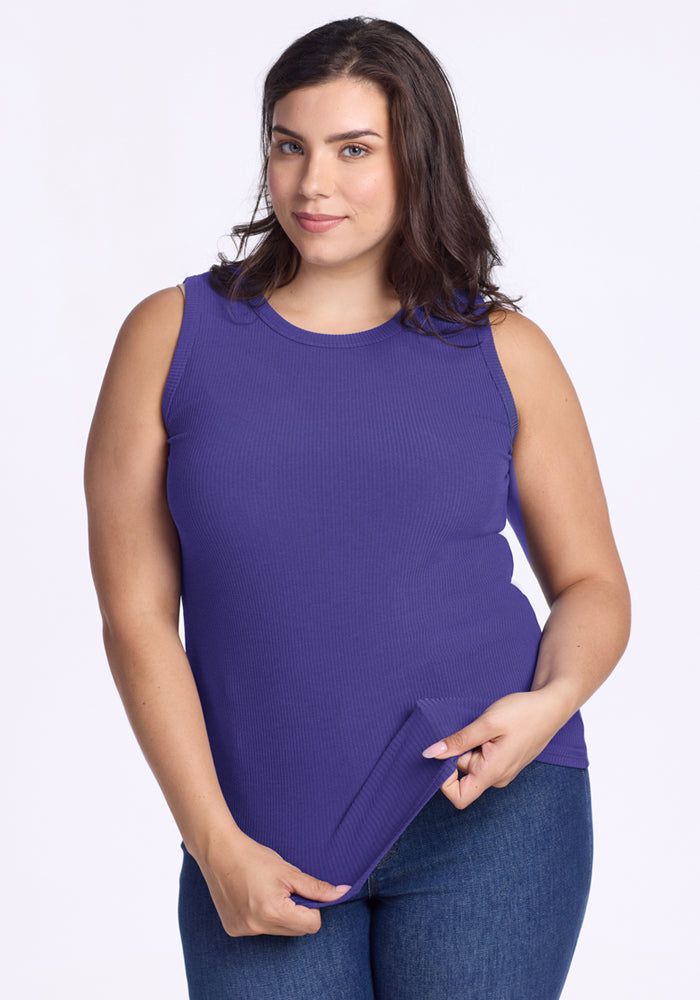 Smiling woman with wavy brown hair wearing Woolx Raegan Ribbed Tank Top in Berry Indigo and blue jeans. 