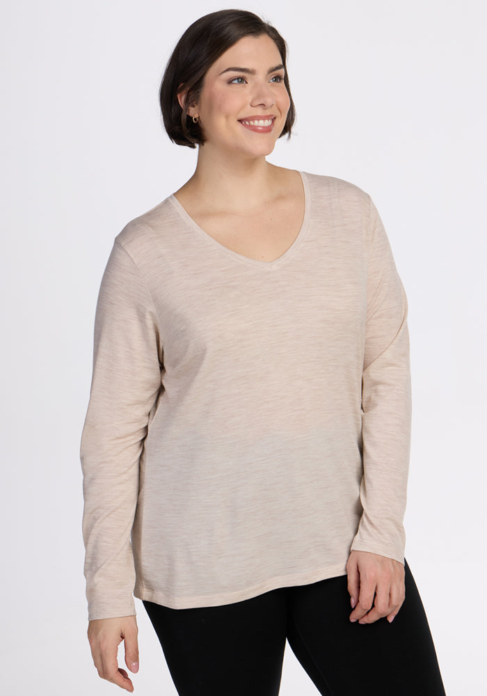 A woman with short brown hair wears the Woolx Millie Long Sleeve in Cream Heather and black pants, smiling against a plain white background. 