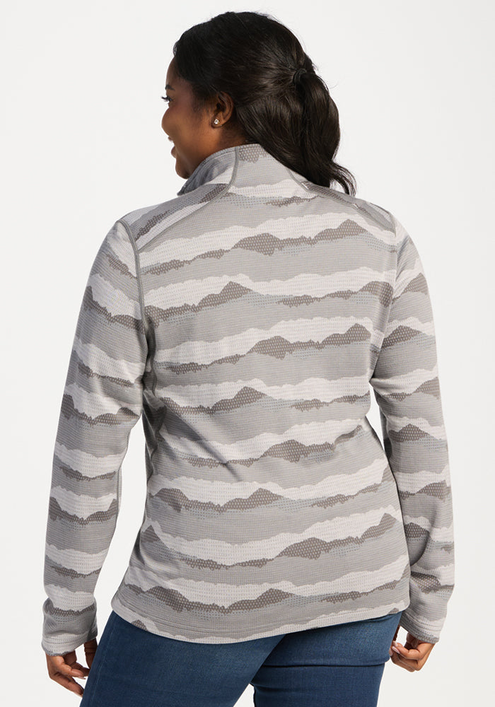 Woman in camo jacket and jeans, perfect over the Woolx Emi 1/4 Zip—High Peaks for all-day comfort and warmth.