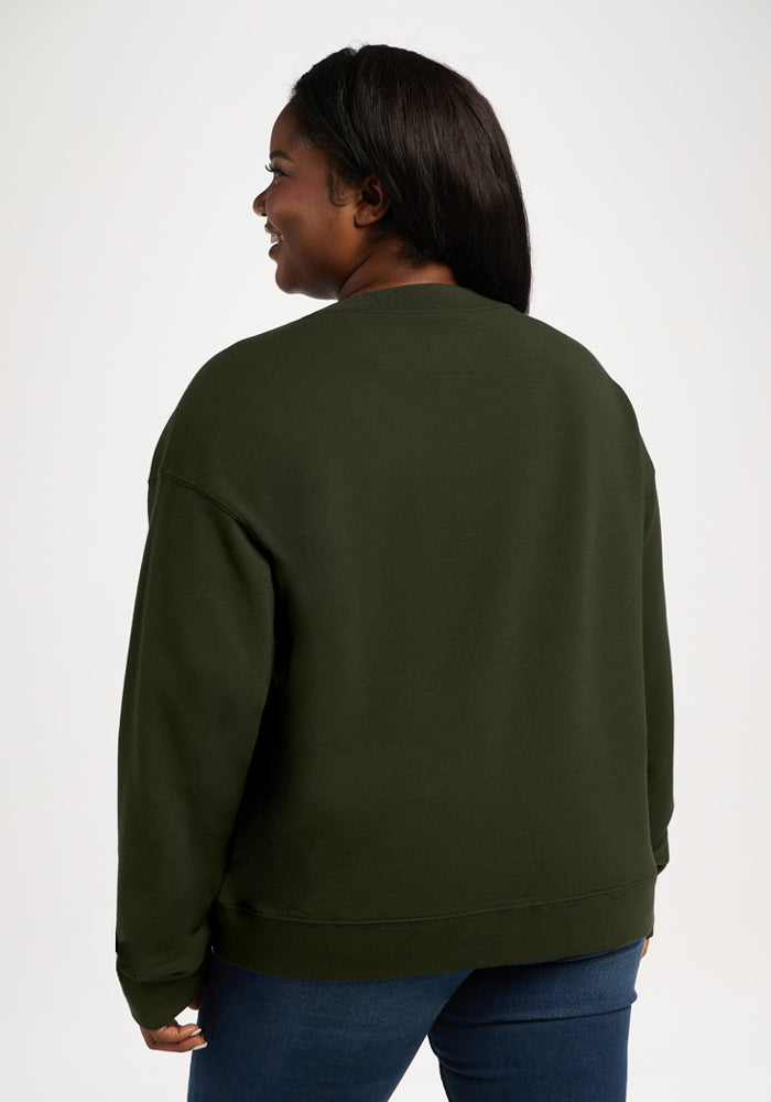 A person seen from behind wearing an olive green Woolx Molly Crewneck - Duffel Bag and blue jeans.