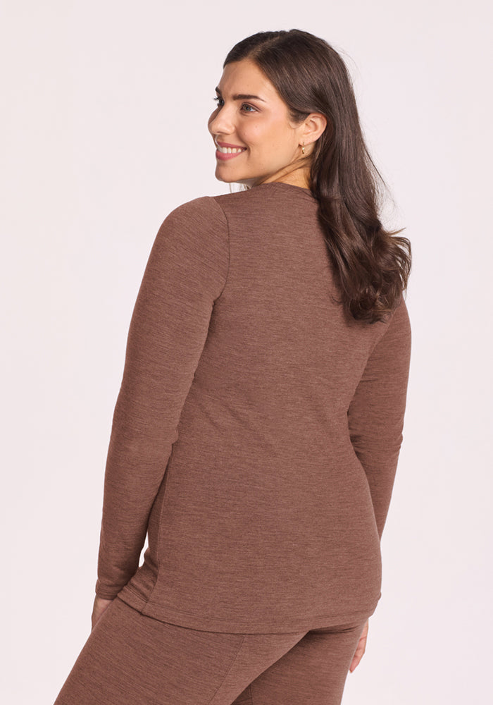 Woman in the Woolx Sadie Baselayer Top in Sable Heather, smiling and looking over her shoulder against a plain background.