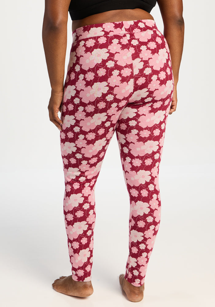 Model in Woolx Taylor Baselayer Leggings - Floral Crush and black top, barefoot, facing away on white background.