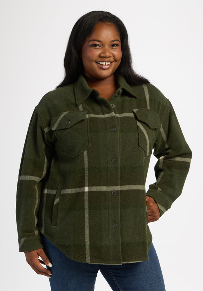 Woman smiles in Woolx Sawyer Shacket - Driftwood Fern Plaid and blue jeans against a plain white background. 