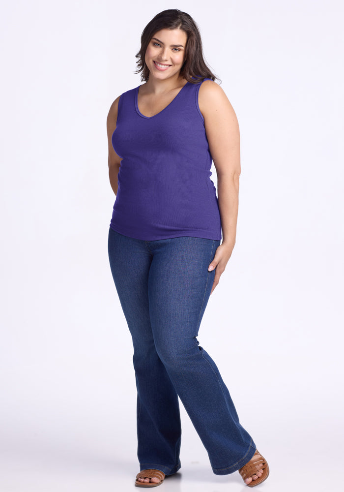 Woman wearing the Woolx Vivi Ribbed Tank in Berry Indigo and blue jeans, smiling against a plain white background.