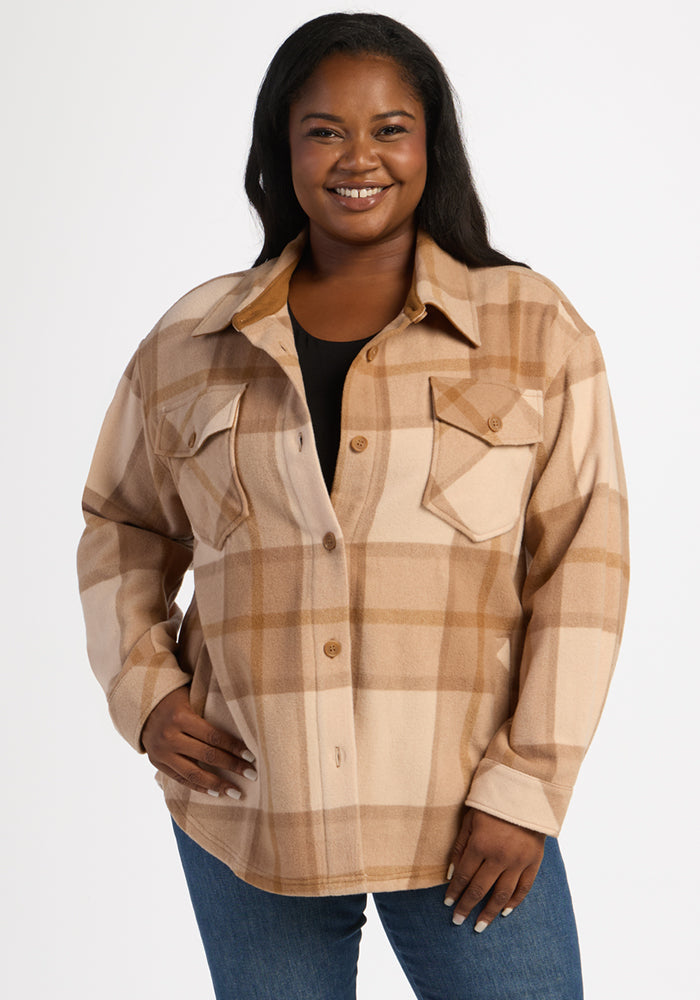 A woman smiles, wearing the Woolx Sawyer Shacket - Saddleback Plaid over a black top and blue jeans. 
