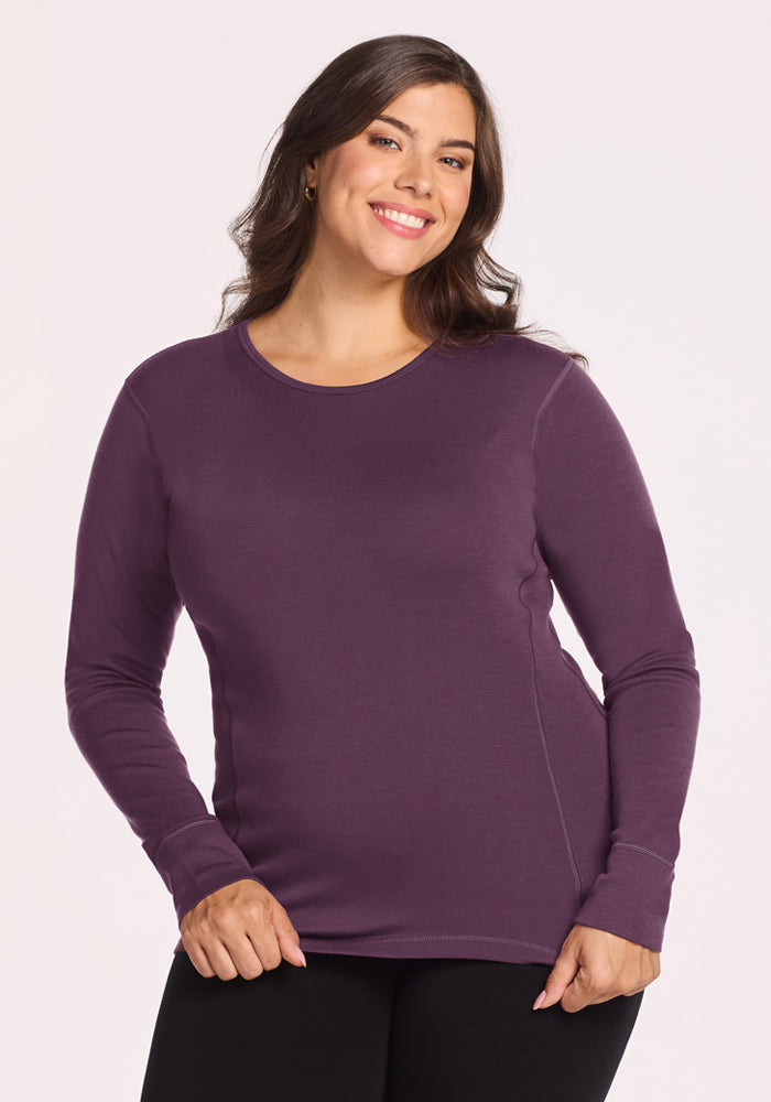 Woman smiling in Woolx Hannah Long Sleeve Top - Purple Iris and black pants, on a plain light background. 