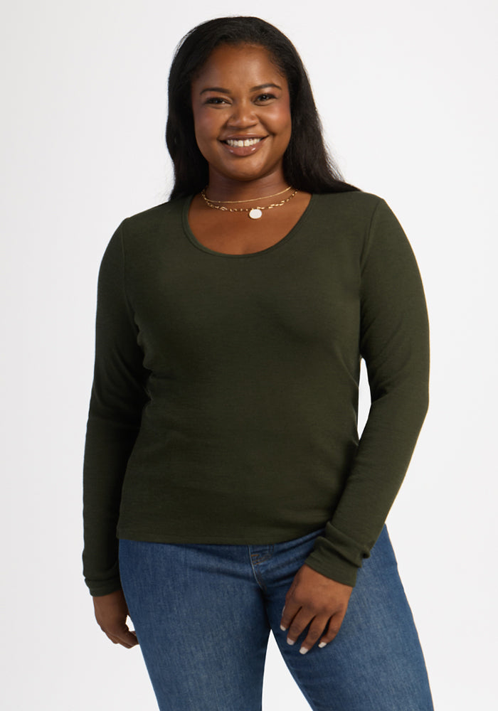 Smiling woman wears the Woolx Katie Ribbed Long Sleeve in Duffel Bag with blue jeans, posing against a white background. 
