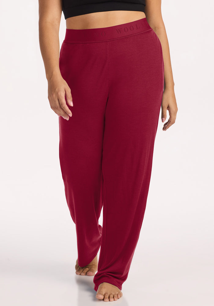 A person wearing beet red Woolx Maya Lounge Pants featuring a high-waisted, wide-leg cut with an elastic waistband. 