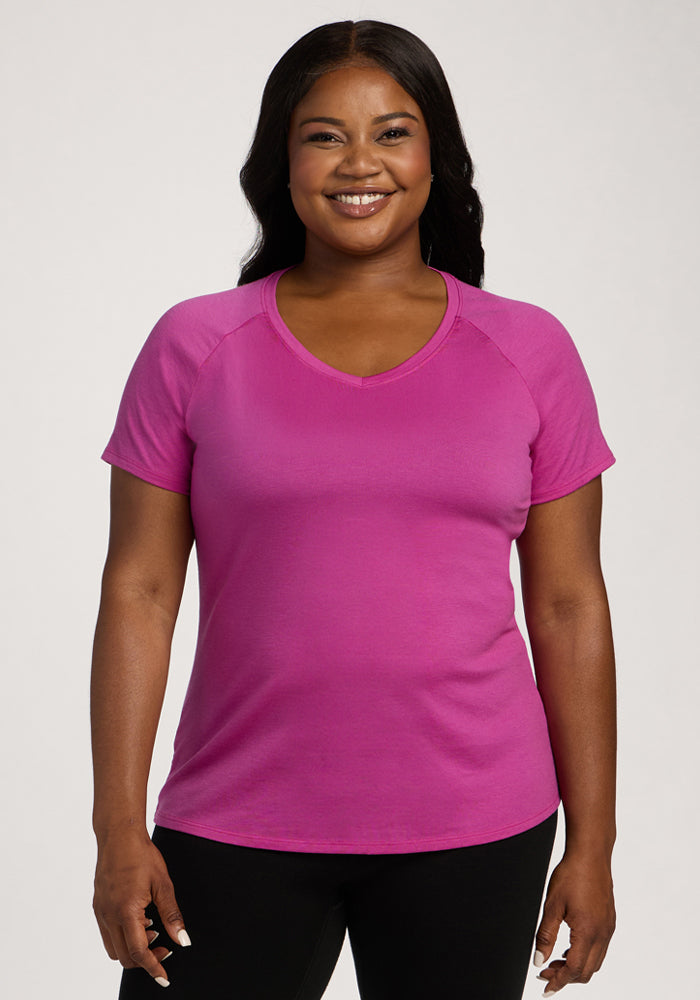 Smiling woman in the Woolx Mia V Neck - Summer Sorbet and black pants against a plain light background. 