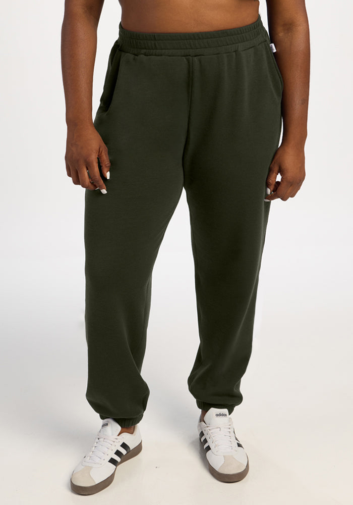 Person wearing Woolx Parker Sweatpants - Duffel Bag and white Adidas sneakers, standing against a white background. 
