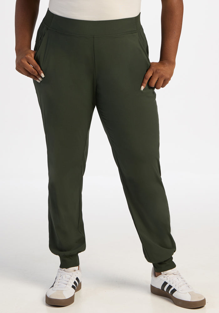 Person wearing Woolx Palmer Joggers - Duffel Bag, white shirt, and white sneakers with black stripes, hands in pockets. 
