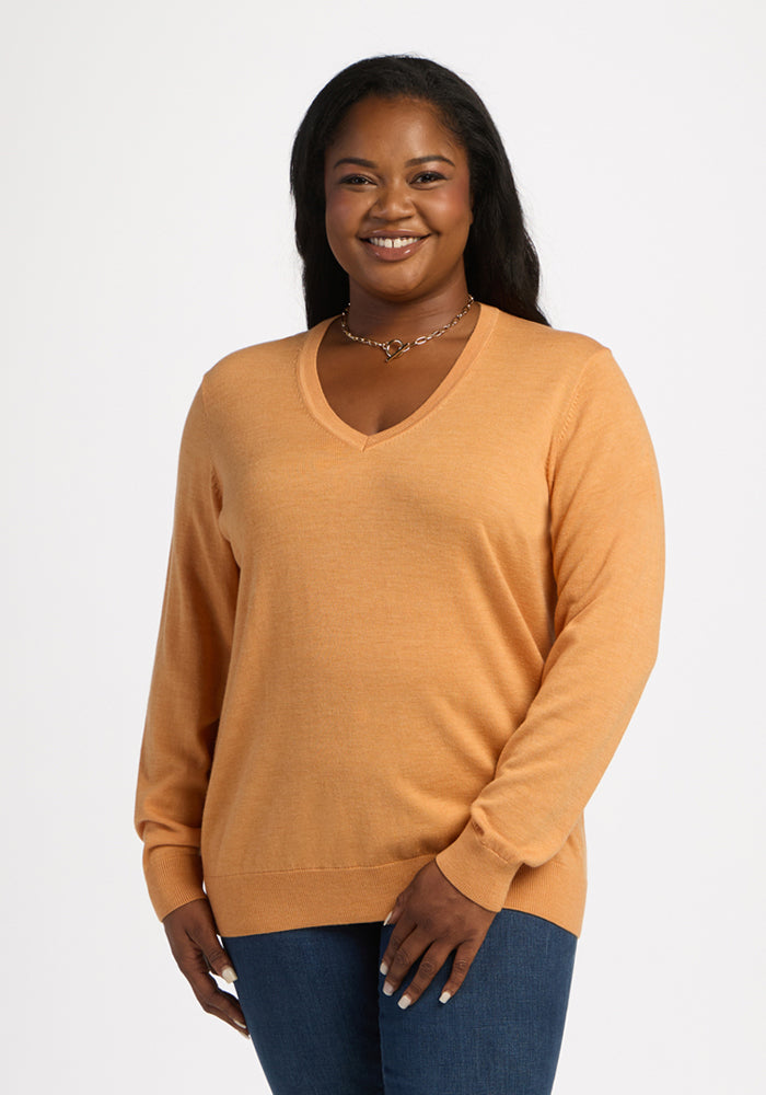 Woman smiling in Woolx Francesca Sweater - Butterscotch and jeans, standing against a plain white background. 