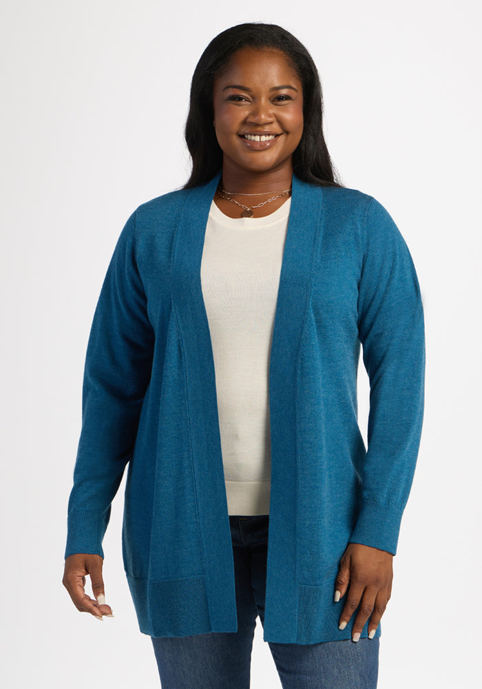 Smiling woman in the Woolx Macie Sweater - Blue Pine, white top, and jeans, posed against a plain white background. 